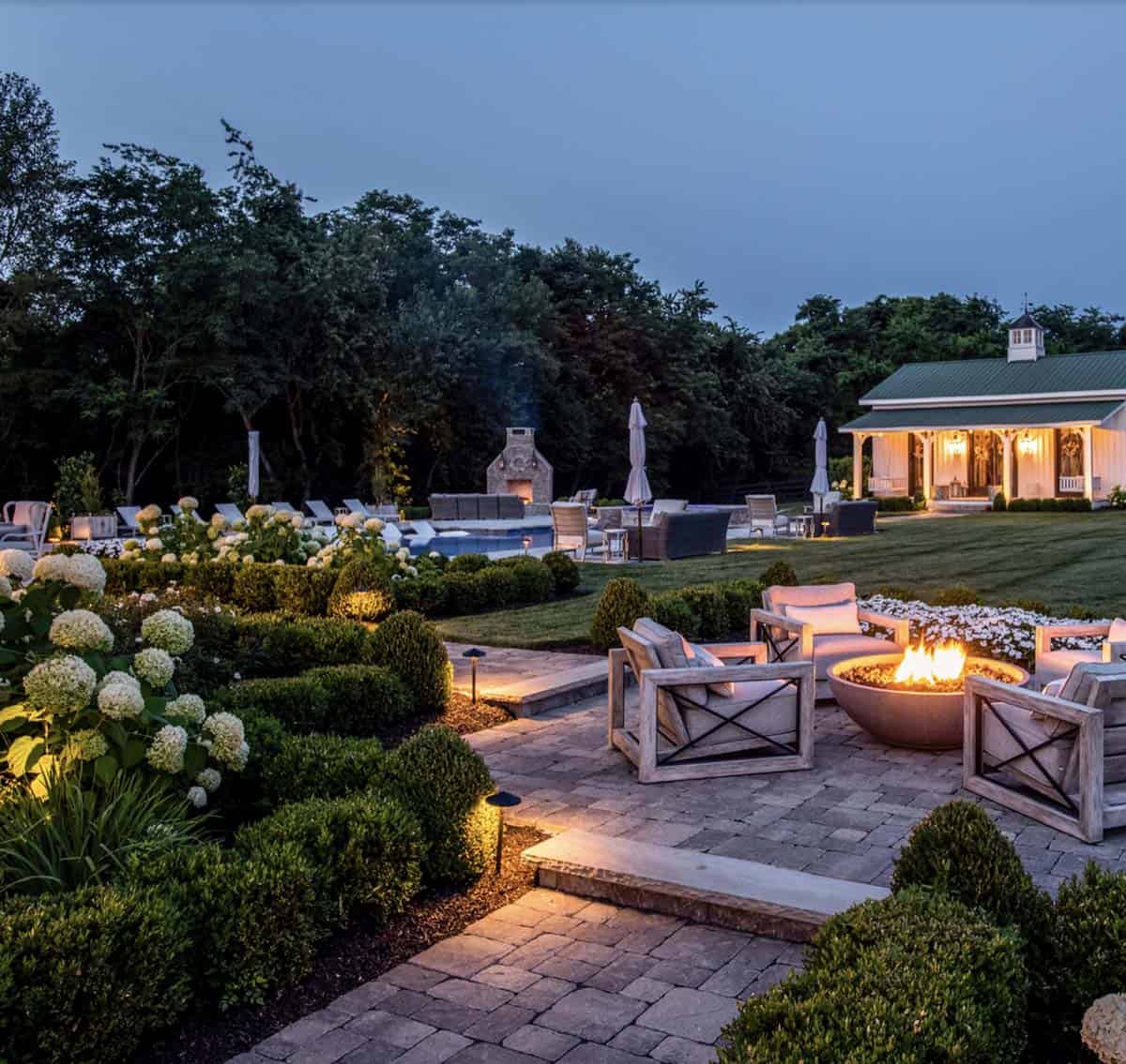 Landscaped backyard with a pool, outdoor fireplace, fire pit, and covered pavilion
