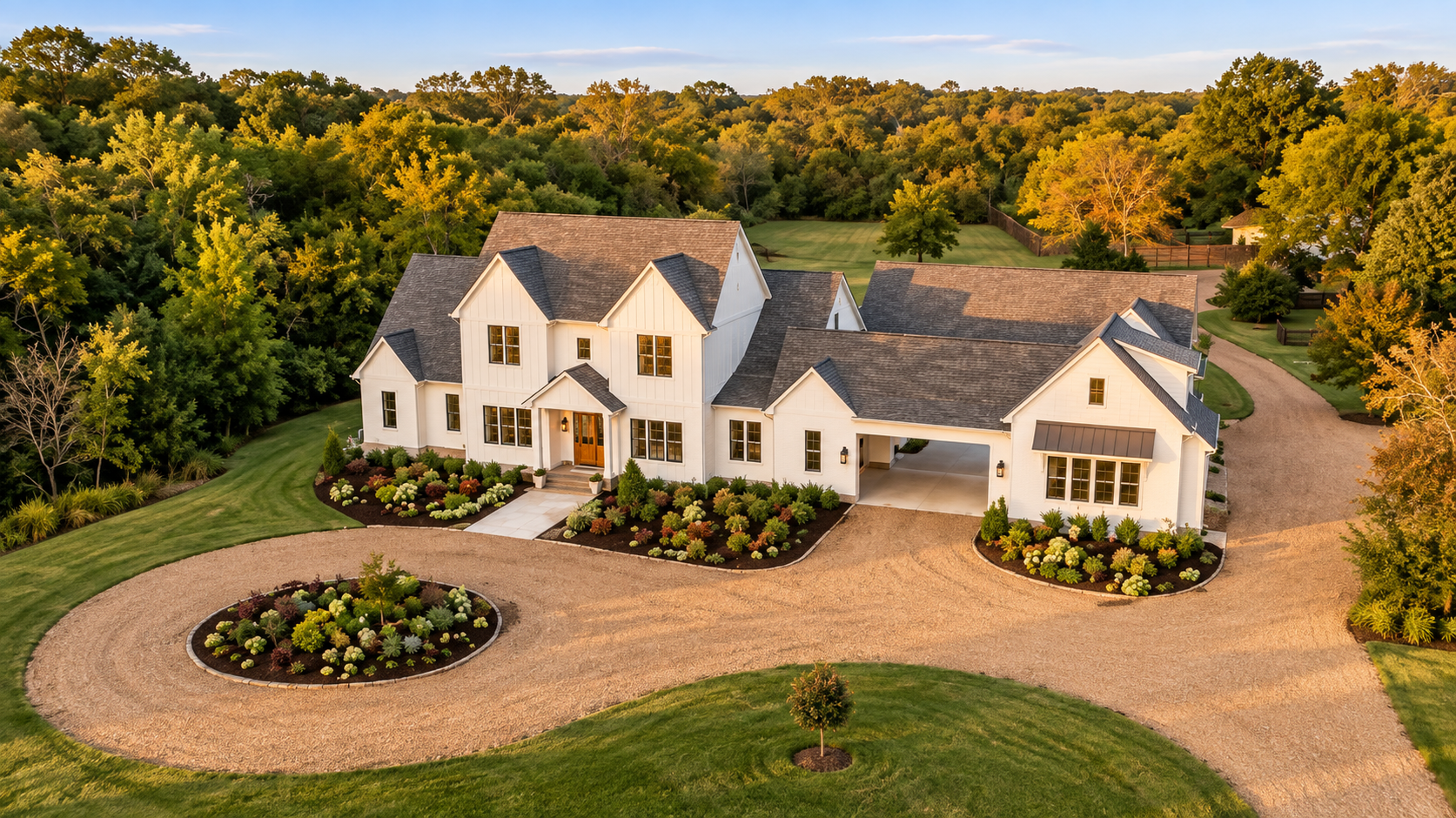 Aerial view of a white country estate with a circular drive, manicured landscaping, and mature trees